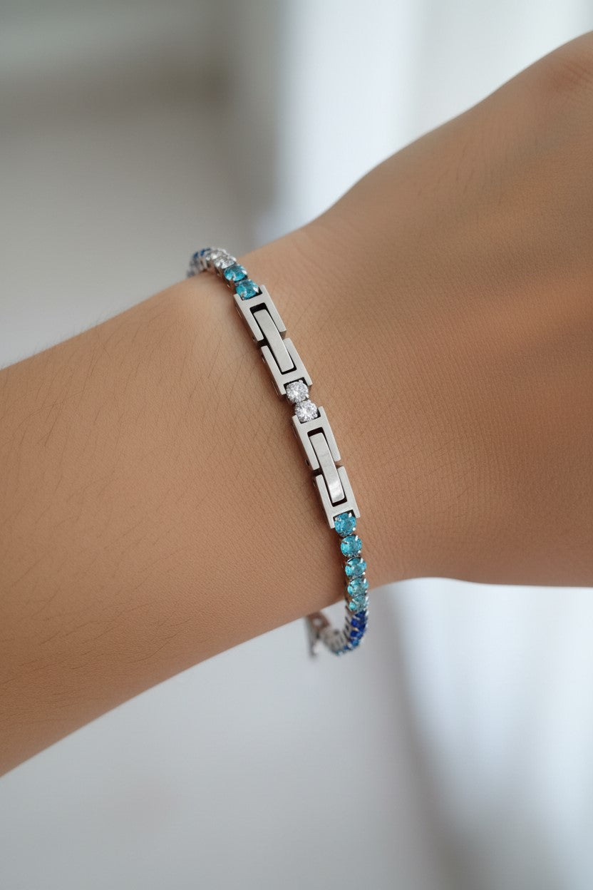 Pulseira tênis prateada com pedras transparentes e coloridas em tons de azul em aço inoxidável. Pode ser combinado com o colar