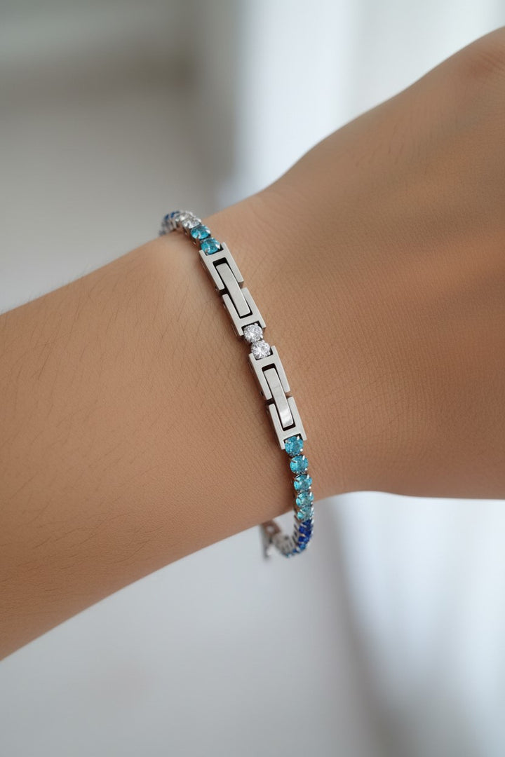 Pulseira tênis prateada com pedras transparentes e coloridas em tons de azul em aço inoxidável. Pode ser combinado com o colar