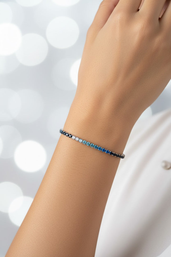 Pulseira tênis prateada com pedras transparentes e coloridas em tons de azul em aço inoxidável. Pode ser combinado com o colar