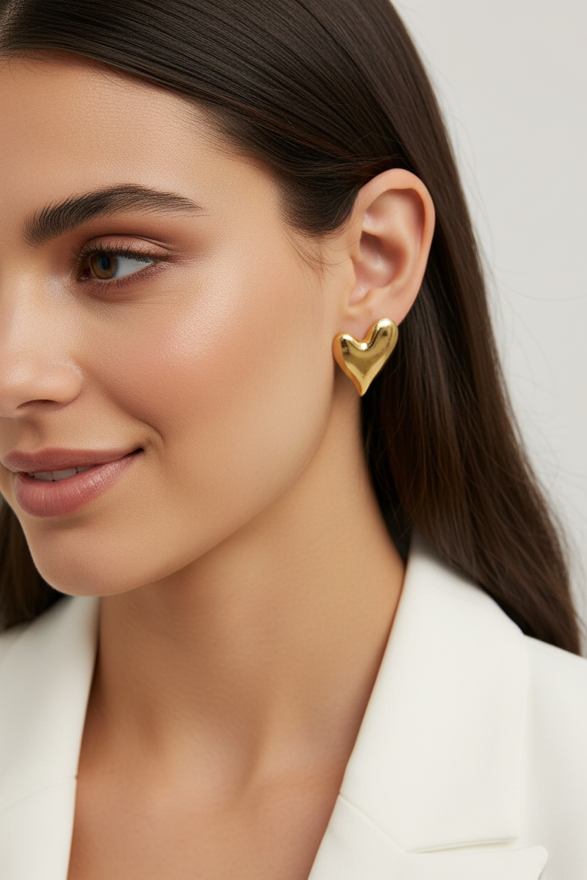 Gold heart earrings on brunette model in white blazer
